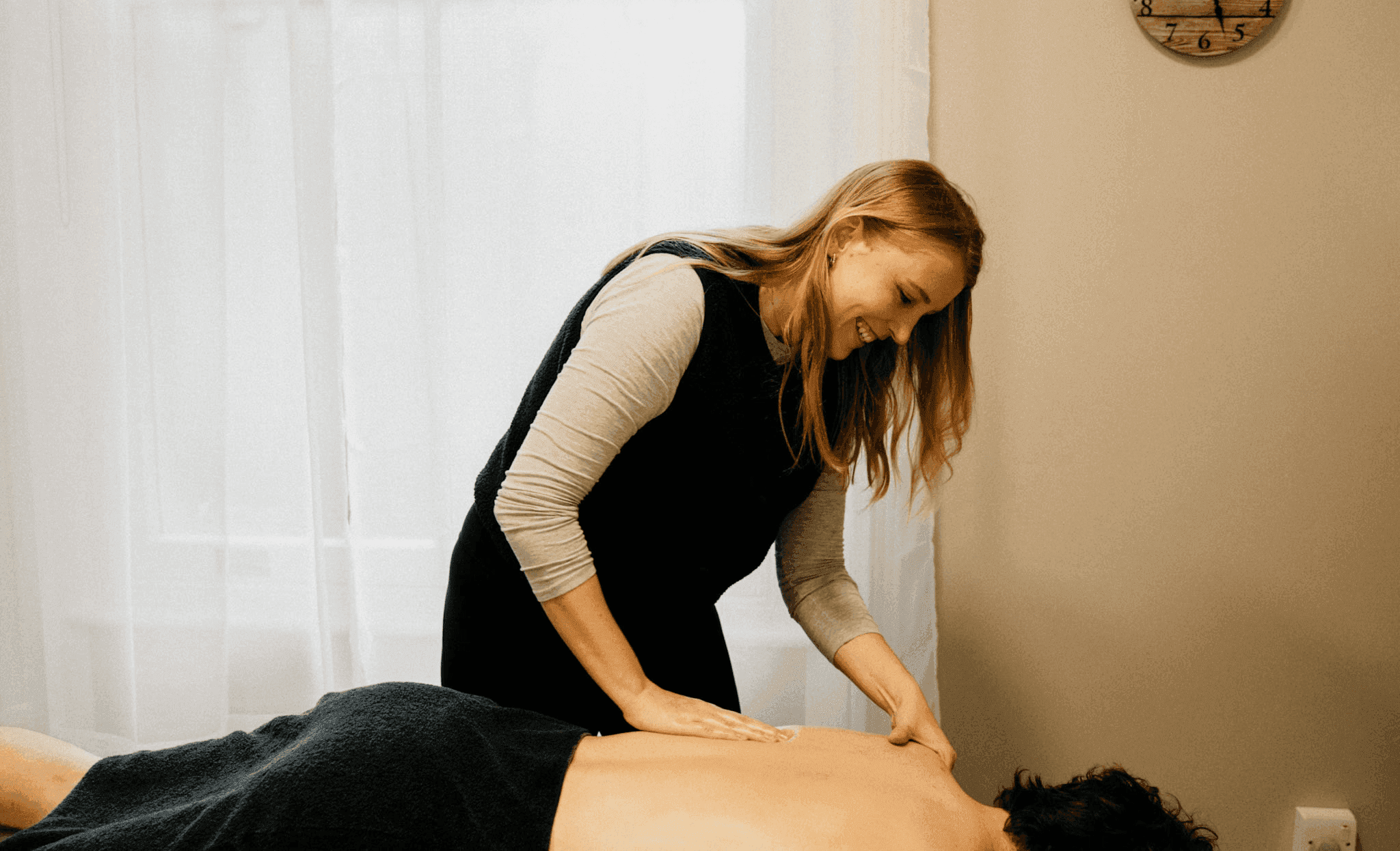 Physiotherapist performing a soft tissue back massage on a client