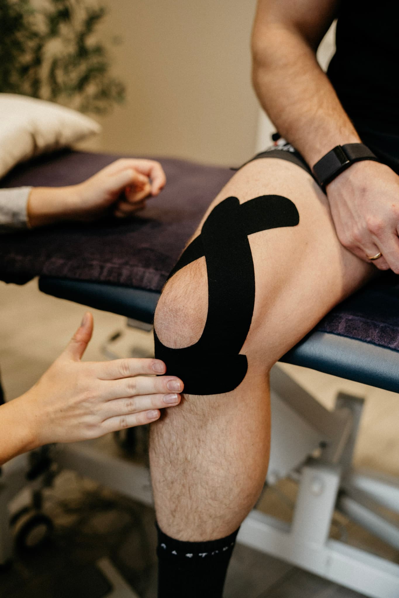 Physiotherapist applying kinesiology tape to a client's knee